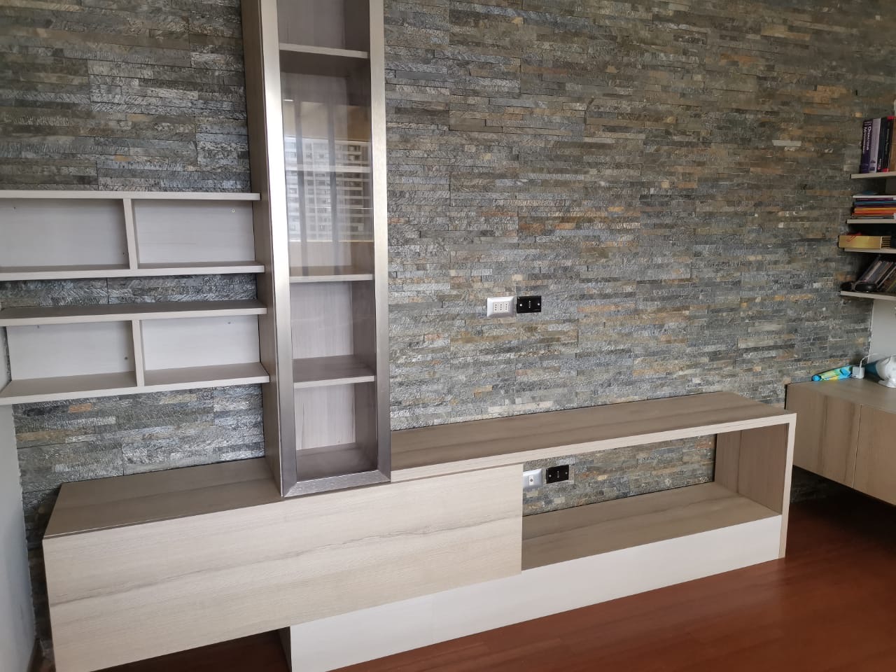 Mueble TV sobre muro de piedra